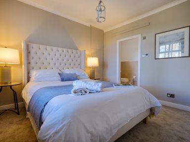 A bedroom with a bed bedside tables lamps and a door leading to a bathroom at Gate House in Killington near Sedbergh