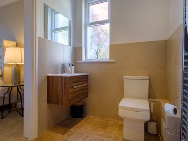 A bathroom with a toilet a wall-mounted wooden vanity with a sink a mirror and a window at Gate House in Killington near Sedbergh