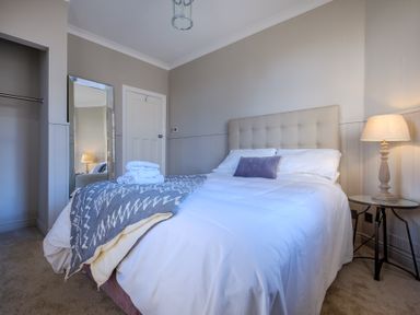 A bedroom with a double bed bedside table and lamp a full length mirror and an open closet at Gate House Killington near Sedbergh