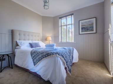 A bedroom with a bed a nightstand a lamp and a window at Gate House in Killington near Sedbergh