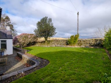 A garden with a grassy lawn stone wall and a tree at Gate House in Killington near Sedbergh