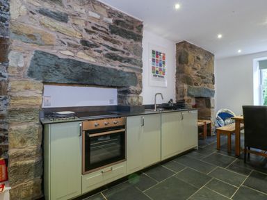A kitchen with a stove and dining area at Ty Capel Bethania in Nant Gwynant
