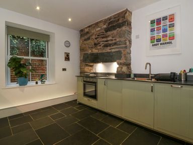 A kitchen with a stone wall and a window at Ty Capel Bethania Nant Gwynant