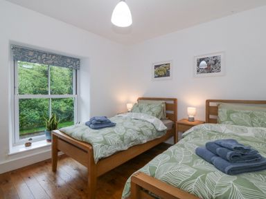A bedroom with two beds and a window at Ty Capel Bethania Nant Gwynant