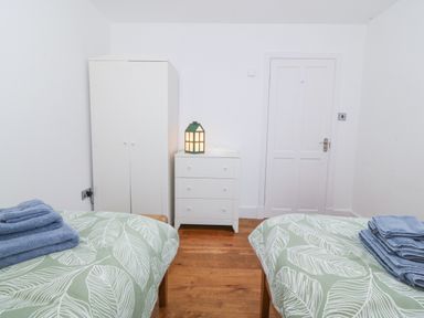A bedroom with two beds, a wardrobe, and a chest of drawers at Ty Capel Bethania in Nant Gwynant