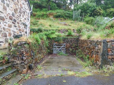 An outdoor area with a gate and stone walls at Ty Capel Bethania Nant Gwynant