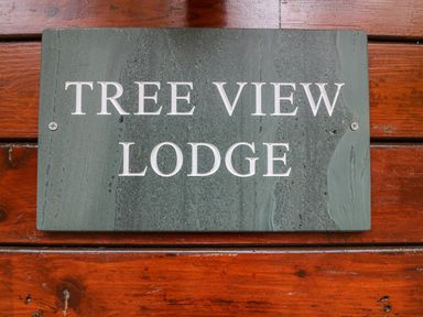 A green stone sign with the text Tree View Lodge mounted on a wooden surface at Tree View Lodge in Troutbeck Bridge