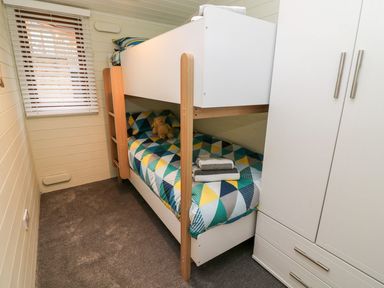A small bedroom with bunk beds and a white wardrobe at Tree View Lodge in Troutbeck Bridge