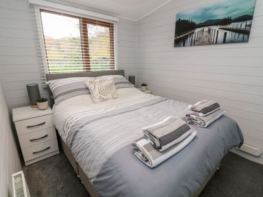 A bedroom with a bed and bedside tables with lamps and plants at Tree View Lodge in Troutbeck Bridge