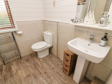 A bathroom with a toilet sink and storage drawers at Tree View Lodge in Troutbeck Bridge