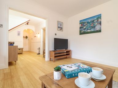 A living room with a wooden table holding two coffee cups and a Scrabble game at Lakeside in Falmouth