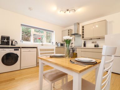 A kitchen with a wooden dining table set for two with tulips at Lakeside in Falmouth