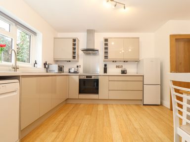 A kitchen with beige cabinets a stainless steel oven a refrigerator and a window at Lakeside in Falmouth
