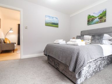 A bedroom with a double bed and folded towels on the bed with a door leading to a living area at Lakeside in Falmouth