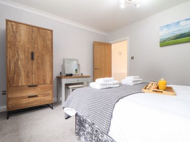 A bedroom with a bed folded towels wardrobe dresser and a door open at Lakeside in Falmouth