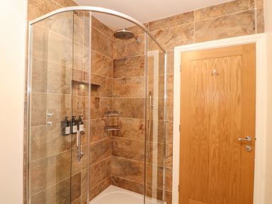 A bathroom with a glass shower enclosure and a wooden door at Lakeside in Falmouth