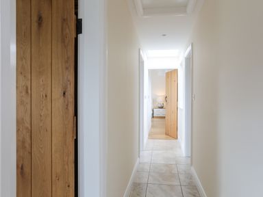 A hallway with tiled floor and wooden doors leading to rooms at The Piggery in LLanfair Talhaiarn near Abergele