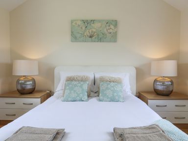 A bedroom with a bed with pillows and two bedside tables with lamps at The Piggery in LLanfair Talhaiarn near Abergele