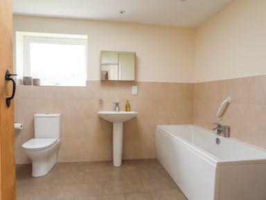 A bathroom with a toilet sink mirror and bathtub at The Piggery in LLanfair Talhaiarn near Abergele