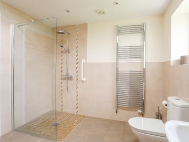 A bathroom with a walk-in shower a toilet a towel radiator and a window at The Piggery in LLanfair Talhaiarn near Abergele