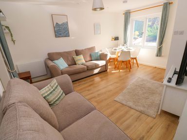 A living room with a sofa and dining area at No.22 The Clicketts in Tenby