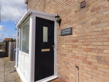 An entrance with a door and sign at Lavender Cottage Beadnell