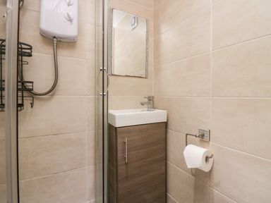 A small bathroom with a shower unit a sink with cabinet and a mirror at High Wreah Bolt Hole in Cleator Moor