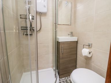 A bathroom with a shower enclosure a sink with cabinet a toilet and a toilet paper holder at High Wreah Bolt Hole in Cleator Moor