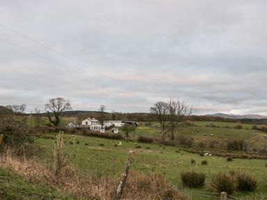 A rural landscape with fields grazing sheep trees and houses at High Wreah Bolt Hole in Cleator Moor