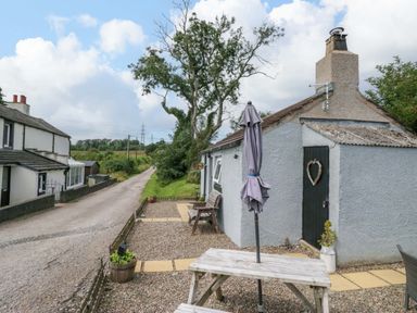 An outdoor area with a table and umbrella at High Wreah Bolt Hole in Cleator Moor