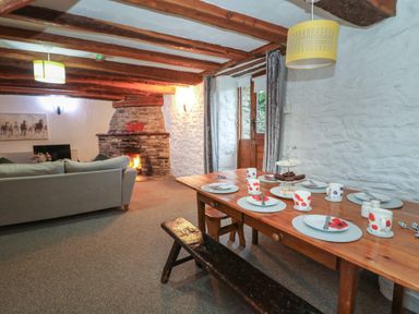 A living room with a wooden dining table set for tea a fireplace and a beige sofa at Ty Ceffylau in Llanllwni near Llanybydder