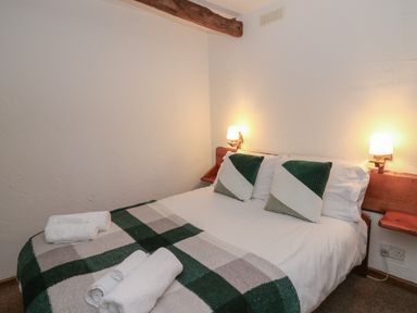 A bedroom with a double bed with green and white pillows and towels on the blanket at Ty Ceffylau in Llanllwni near Llanybydder