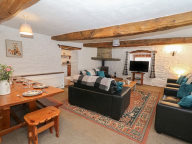 A living room with sofas a wooden dining table and a television at Y Beudy in Cwmiar near Llanybydder