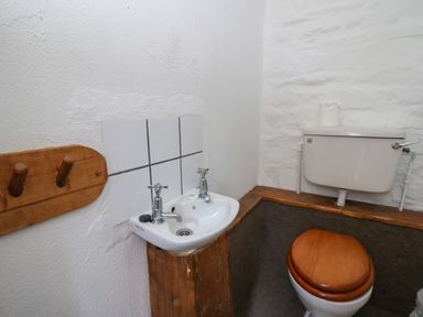 A small bathroom with a white sink and wooden toilet seat at Y Beudy in Cwmiar near Llanybydder