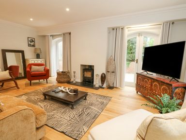 A living room with a wooden coffee table a patterned rug armchairs and a television on a decorated cabinet at Sunningdale Rise in Preston