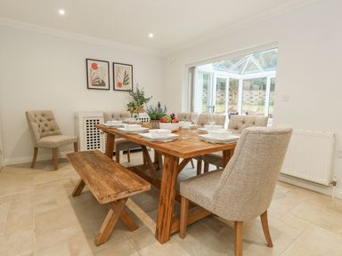 A dining room with a wooden table set for six people and a wooden bench at Sunningdale Rise in Preston