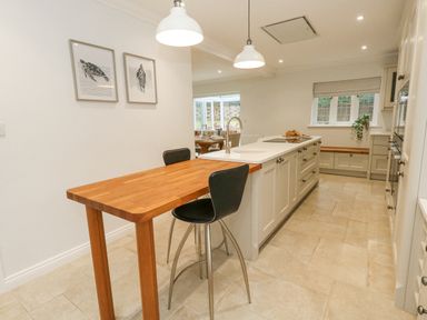 A kitchen with a wooden breakfast bar and stools framed sea turtle prints on a wall at Sunningdale Rise in Preston