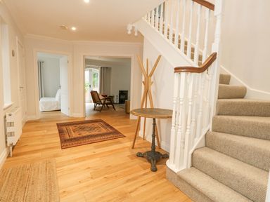An entrance hall with a staircase a small round table a coat rack and an area rug at Sunningdale Rise in Preston