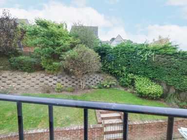 A backyard with grass lawn shrubs trees and steps behind a black railing at Sunningdale Rise in Preston