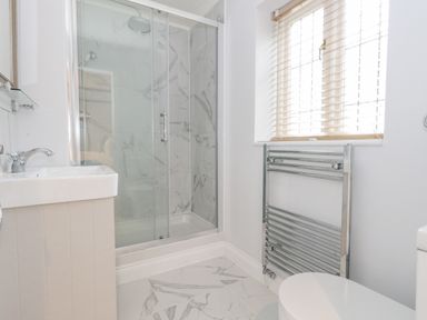 A bathroom with a shower enclosure sink toilet chrome towel radiator and window blinds at Sunningdale Rise in Preston