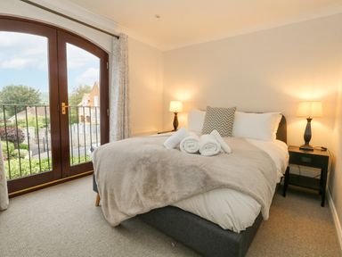 A bedroom with a double bed two bedside tables with lamps and a balcony door at Sunningdale Rise in Preston
