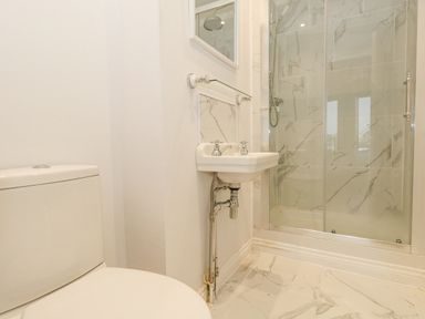 A bathroom with a toilet sink and a shower with glass doors at Sunningdale Rise in Preston