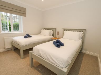 A bedroom with two single beds with white bedding and blue towels on them at Sunningdale Rise in Preston