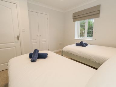 A bedroom with two single beds with white bedding and folded blue towels on each bed and a window with a blind at Sunningdale Rise in Preston