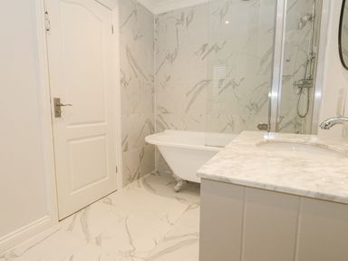 A bathroom with a clawfoot bathtub a marble countertop sink a shower area and tiled walls and floor at Sunningdale Rise in Preston
