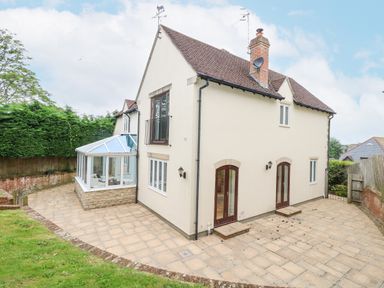 A two-story house with a tiled roof a glass conservatory and paved patio area at Sunningdale Rise in Preston