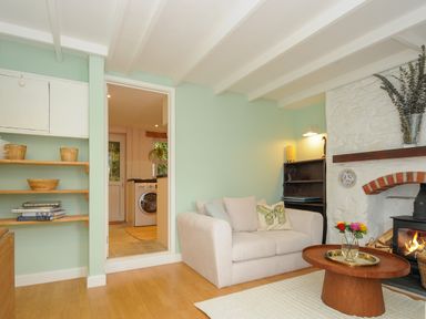 A living room with a beige sofa and wooden coffee table in front of a fireplace at 15 The Moors in Lostwithiel