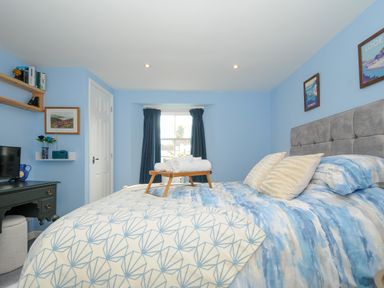 A bedroom with a bed with blue and white bedding and wooden tray with towels at 15 The Moors in Lostwithiel
