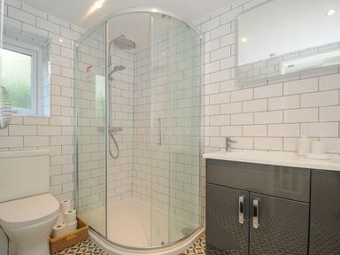 A bathroom with a glass shower enclosure a toilet a sink with a cabinet and a mirror at 15 The Moors in Lostwithiel
