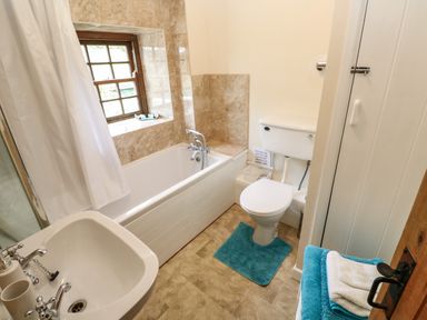 A bathroom with a bathtub shower toilet sink and towels at Swallow Cottage in Mawgan
